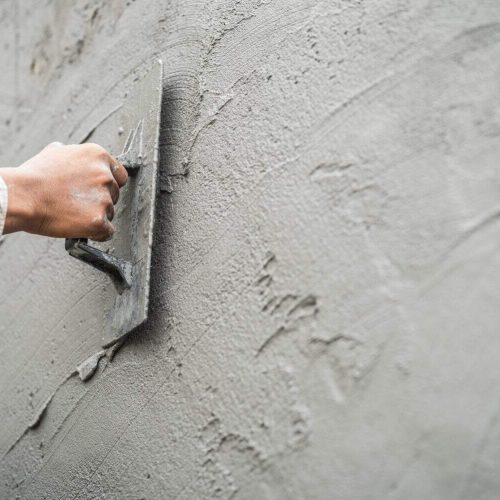 Hand worker plastering cement wall with rough concrete for smooth building wall well free space